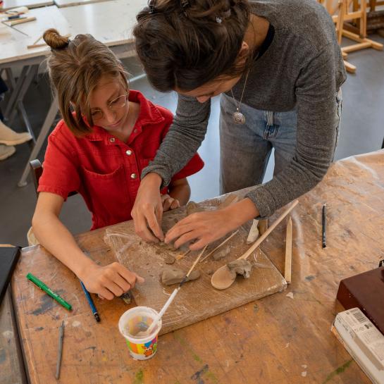 leerkracht helpt meisje met kunstwerkje